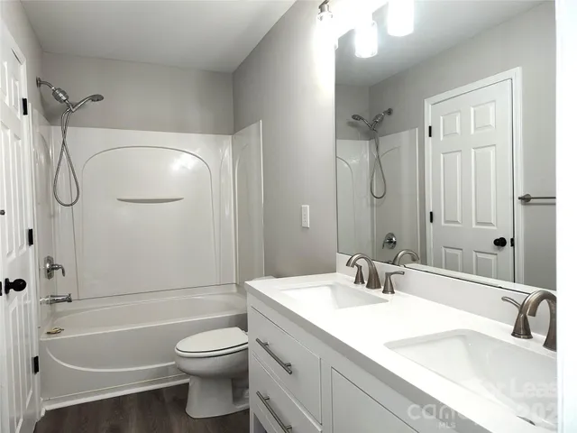 a bathroom with a granite countertop sink a toilet and shower