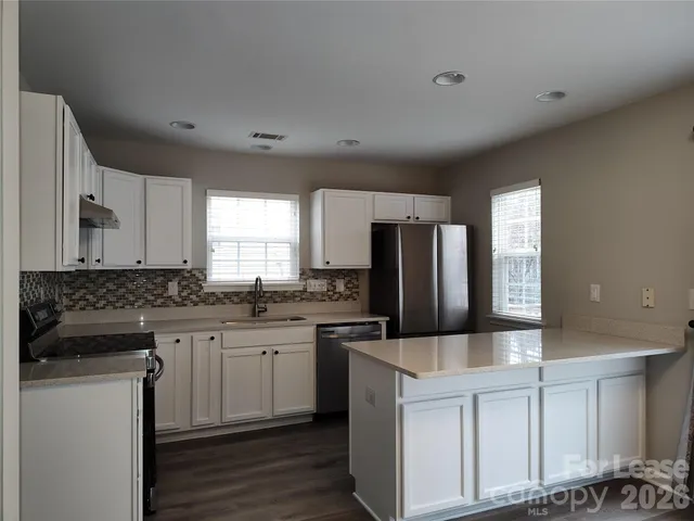 a kitchen with granite countertop a sink stove refrigerator and cabinets
