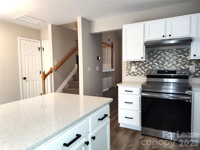 a kitchen with a stove and white cabinets