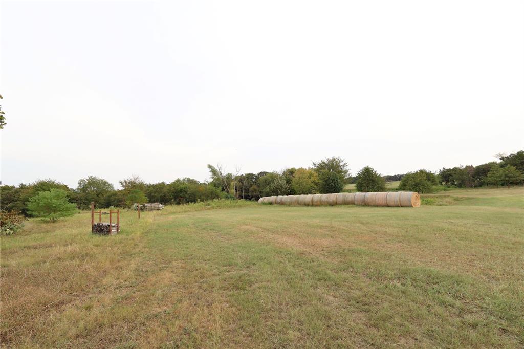 2142 Spring Hill Road Aubrey, TX 76227 - Photo 7 of 18 Expansive open field with scattered trees and a line of hay bales