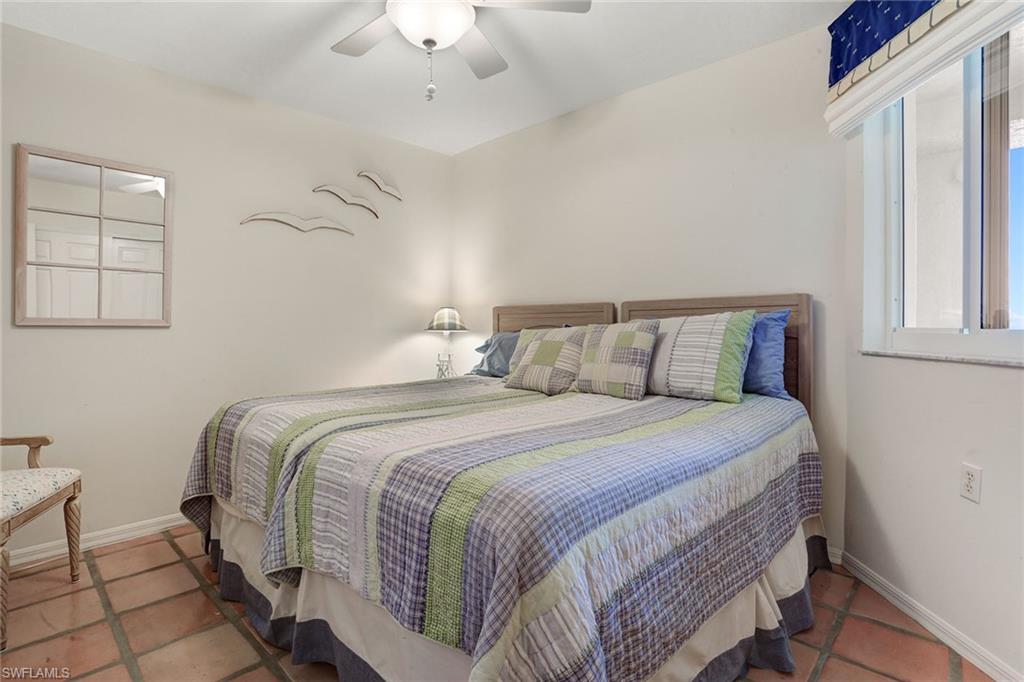50 Seagate Drive, Unit 402B Naples, FL 34103 - Photo 14 of 26 a bedroom with a bed and a chandelier