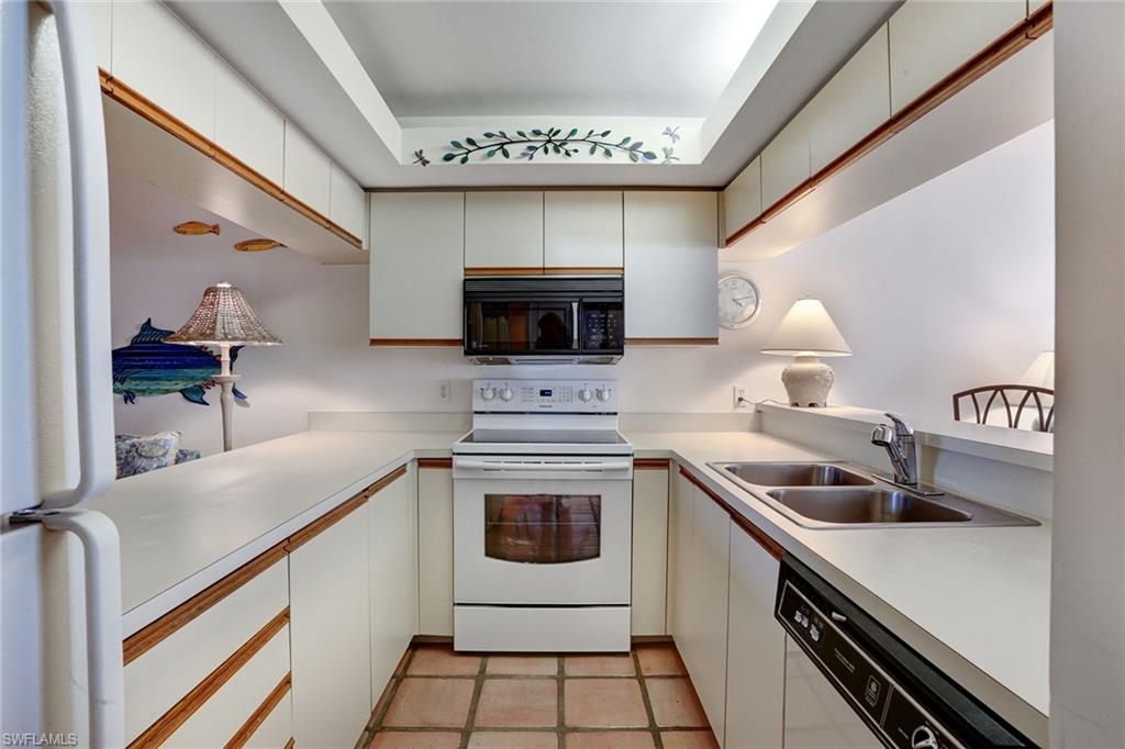 50 Seagate Drive, Unit 402B Naples, FL 34103 - Photo 6 of 26 a kitchen with a sink cabinets and appliances
