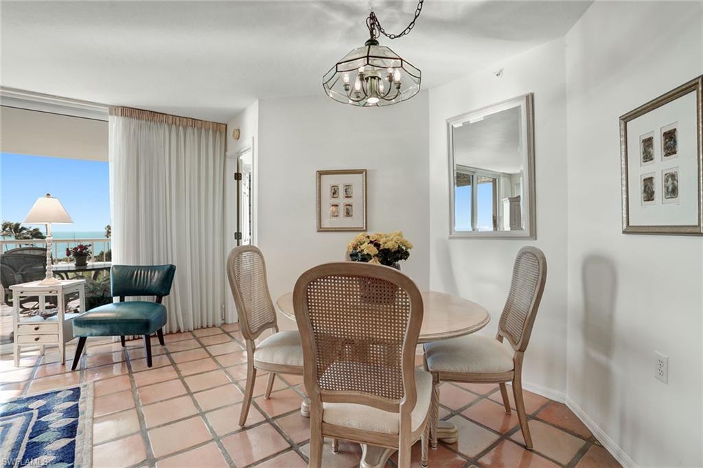 50 Seagate Drive, Unit 402B Naples, FL 34103 - Photo 8 of 26 a dining room with furniture and a chandelier