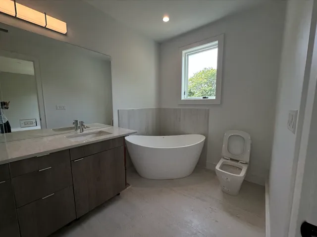 a bathroom with a granite countertop sink a toilet and mirror