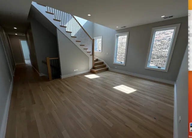 a view of an empty room with wooden floor and stairs