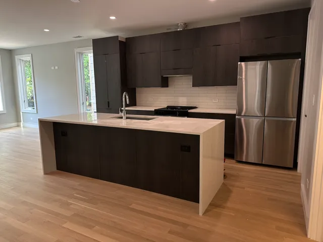 a kitchen with kitchen island a counter top space cabinets and stainless steel appliances
