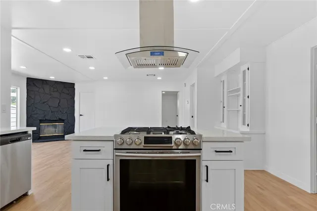 an empty room with wooden floor fireplace and windows