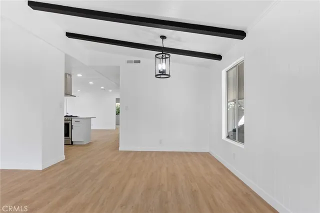 a large kitchen with stainless steel appliances granite countertop a stove top oven a sink and white cabinets