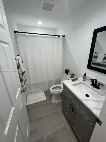 a bathroom with a sink a toilet a mirror and shower