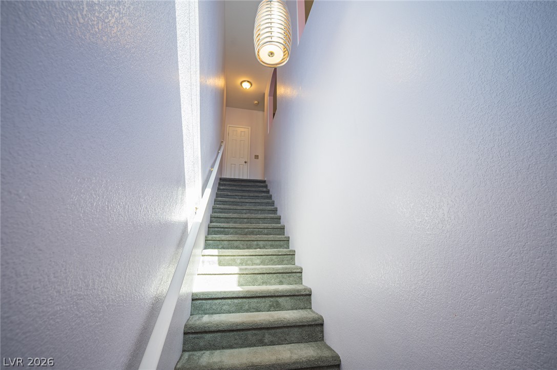 A carpeted staircase ascends between smooth walls to an upper landing.