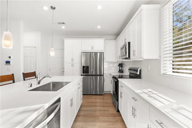 a kitchen with a sink a counter top space stainless steel appliances a window and a refrigerator