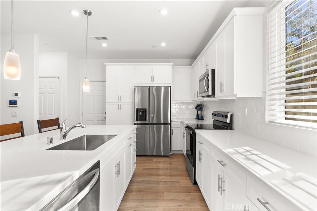 904 Maya Crossing, Unit 19 Lake Elsinore, CA 92530 - Photo 4 of 25 a kitchen with a sink a counter top space stainless steel appliances a window and a refrigerator