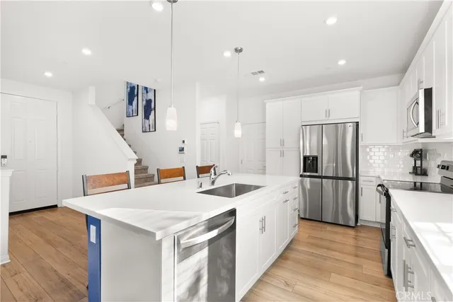 a kitchen with a sink appliances and wooden floor