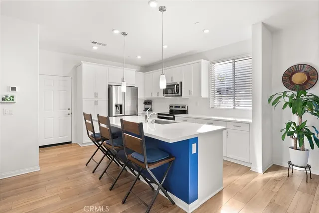 a kitchen with granite countertop kitchen island stainless steel appliances a table chairs sink and cabinets