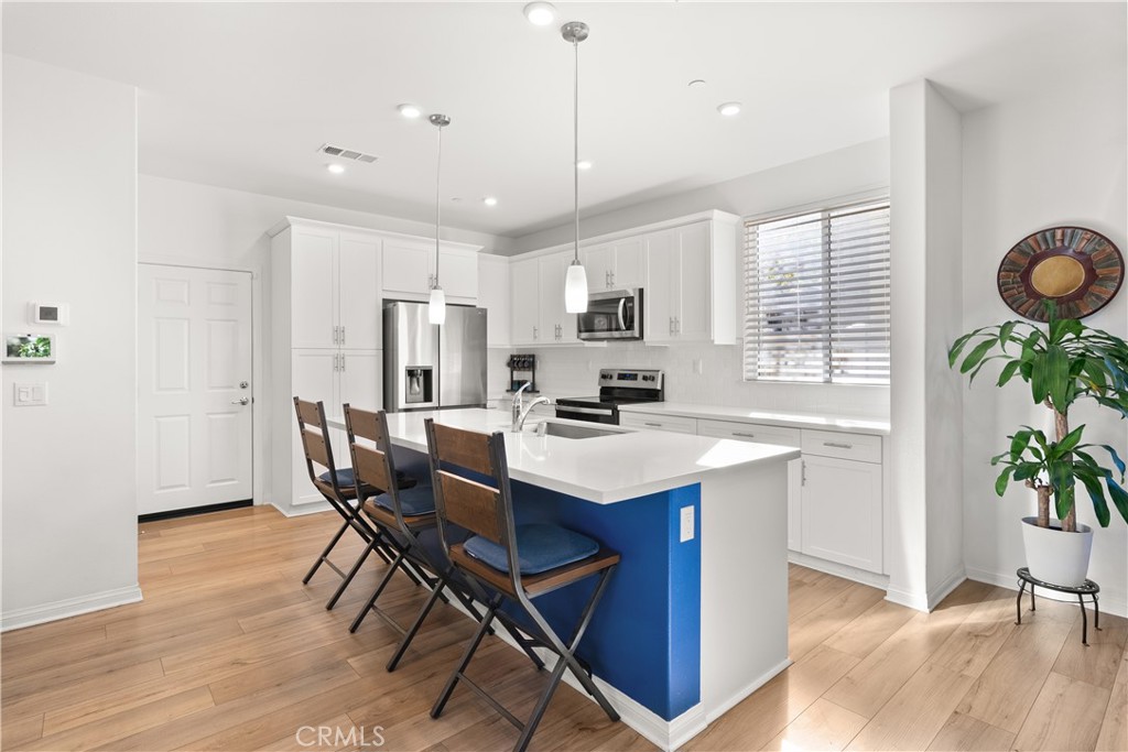 904 Maya Crossing, Unit 19 Lake Elsinore, CA 92530 - Photo 6 of 25 a kitchen with granite countertop kitchen island stainless steel appliances a table chairs sink and cabinets