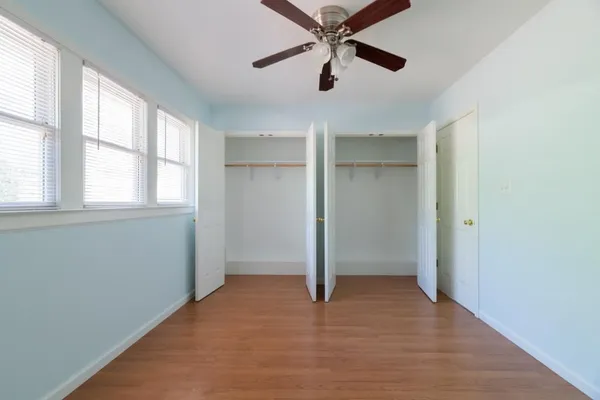 an empty room with chandelier fan and windows