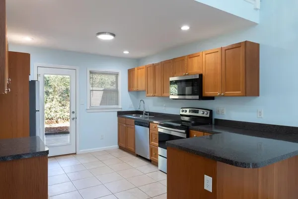 a kitchen with stainless steel appliances granite countertop a stove a sink and a microwave