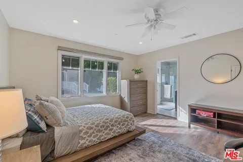 a bedroom with a bed a dresser and a large window