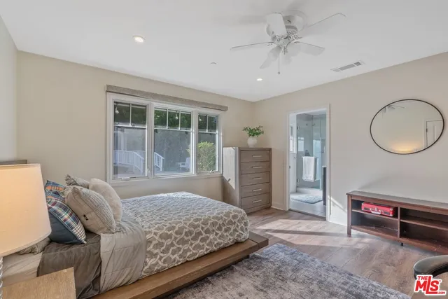 a bedroom with a bed a dresser and a large window