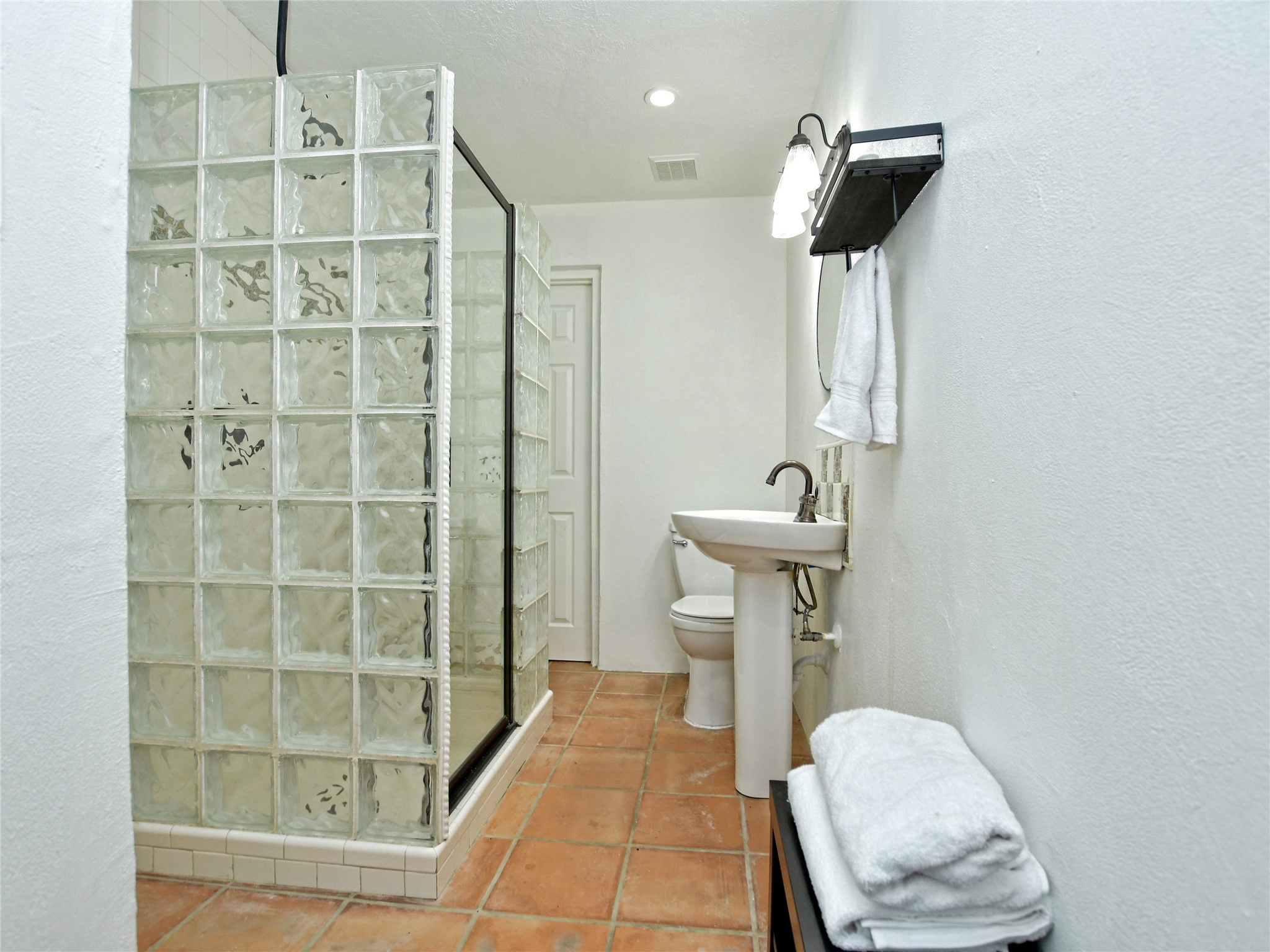 17123 Rocky Ridge Road Austin, TX 78734 - Photo 20 of 26 Bathroom featuring a glass block shower enclosure, terracotta tile flooring, pedestal sink, and recessed lighting