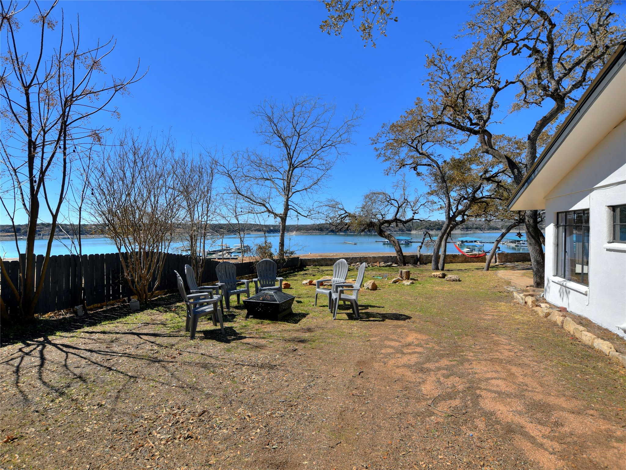 17123 Rocky Ridge Road Austin, TX 78734 - Photo 23 of 26 Lakeside property featuring a spacious yard, mature trees, white exterior siding, and a privacy fence