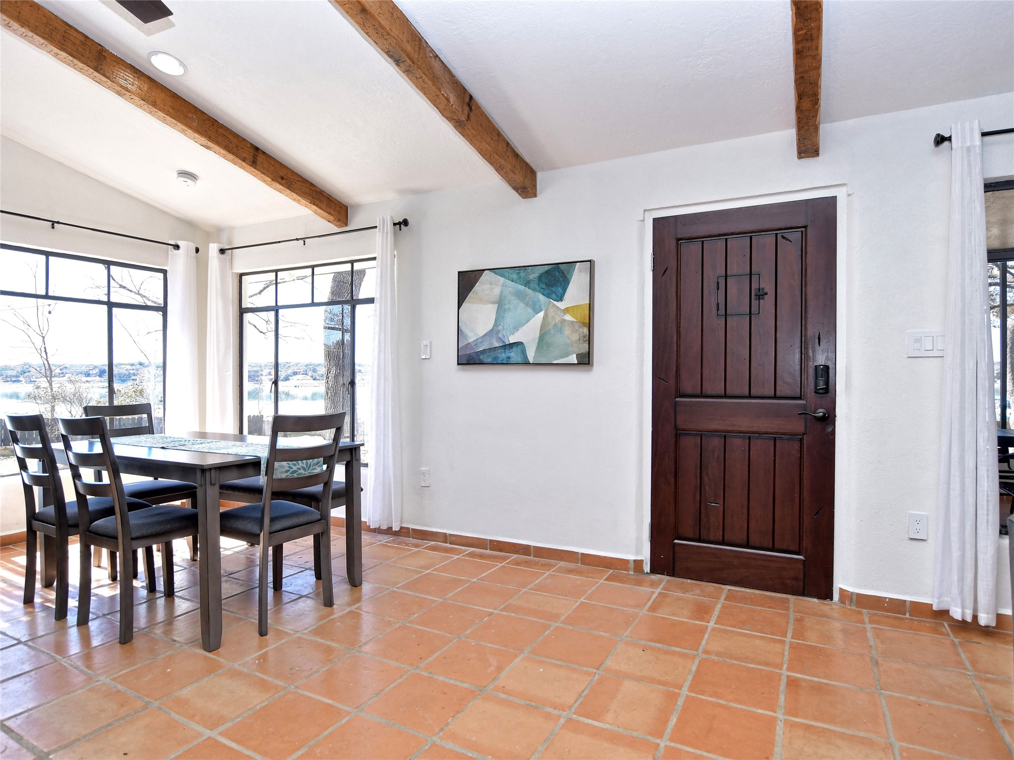 17123 Rocky Ridge Road Austin, TX 78734 - Photo 6 of 26 White walls with exposed wood beams, large windows, and terra cotta tile flooring