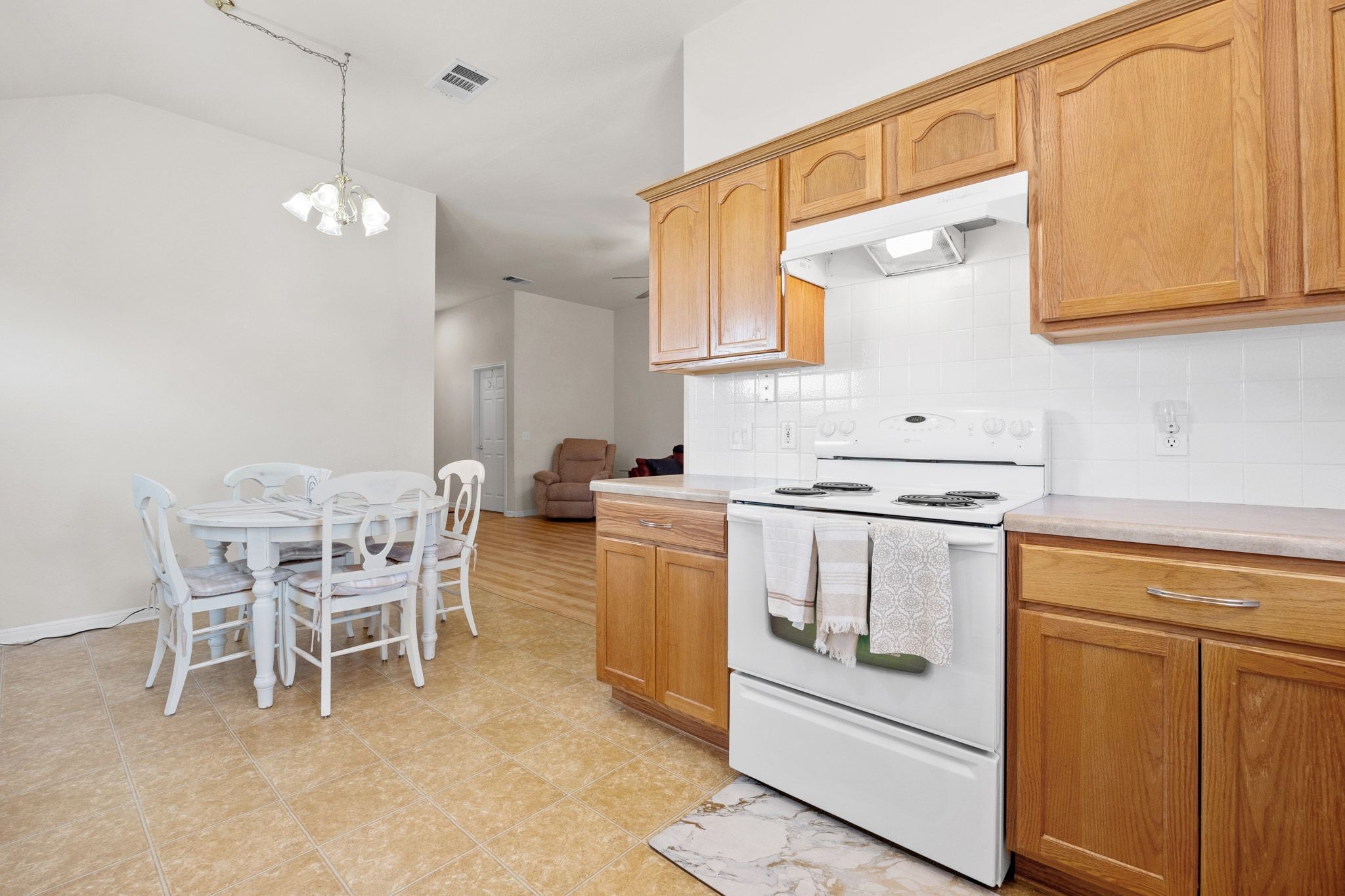 901 Kenneys Way Round Rock, TX 78665 - Photo 16 of 33 Kitchen with electric range, under cabinet range hood, backsplash, light countertops, and vaulted ceiling