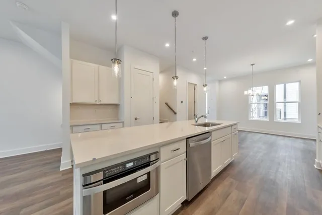 a kitchen with a stove a sink and wooden floor