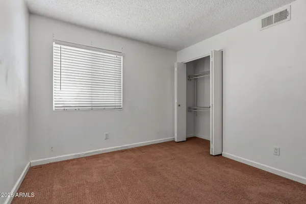 a view of an empty room with closet and a window