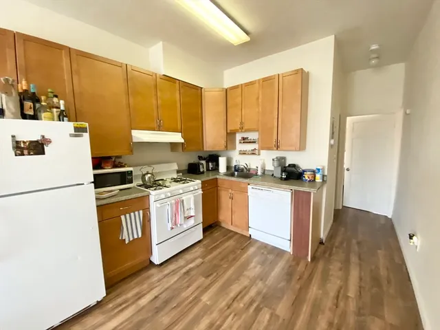 a kitchen with a refrigerator a stove cabinets and wooden floor