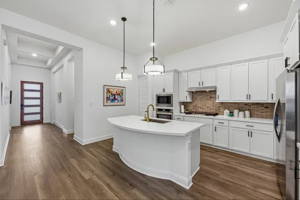 a kitchen with a sink a stove a refrigerator and white cabinets