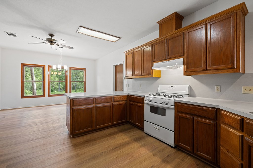 244 Woodway Elgin, TX 78621 - Photo 16 of 40 a kitchen with stainless steel appliances granite countertop wooden cabinets a stove a sink and dishwasher with wooden floor