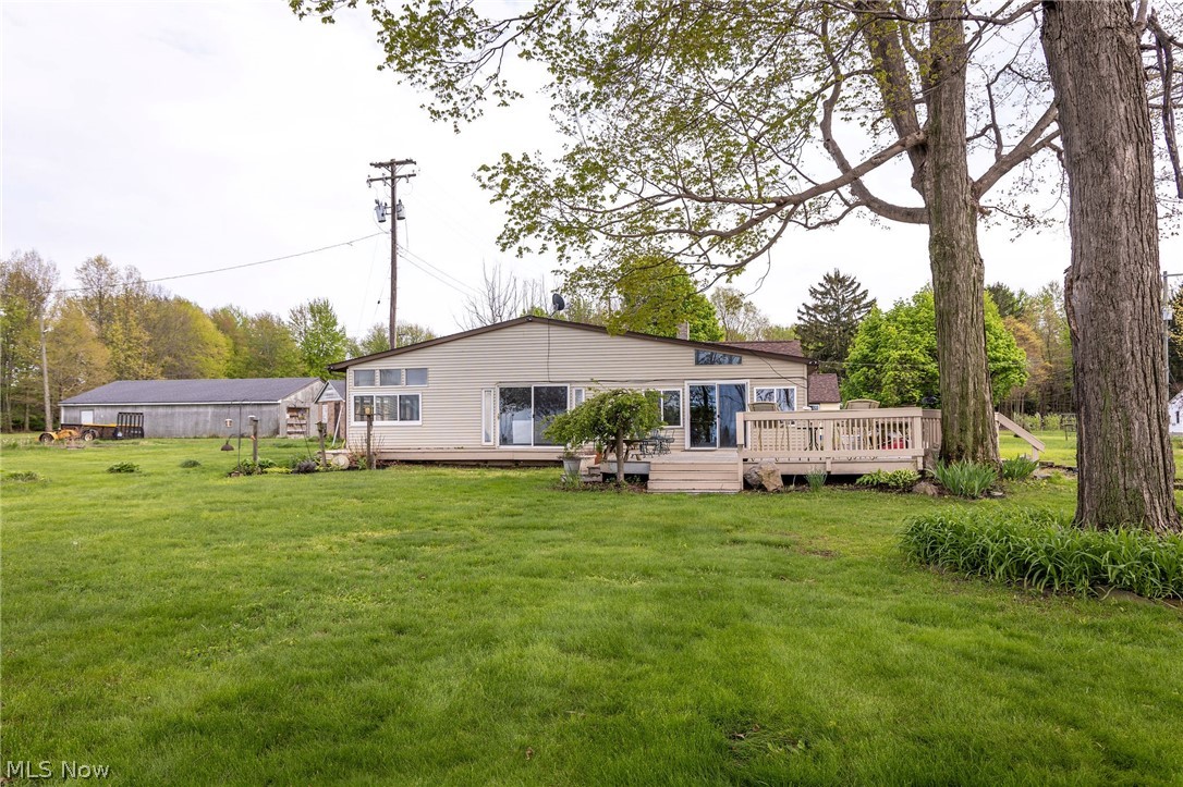 5467 Chapel Road Madison, OH 44057 - Photo 2 of 50 Rear exterior featuring a spacious wood deck with railings, multiple sliding glass doors, horizontal siding, and large picture windows