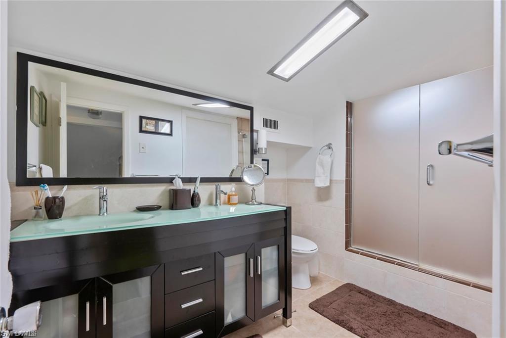 3550 Hazel Road Naples, FL 34104 - Photo 21 of 43 a bathroom with a granite countertop sink a toilet and a mirror