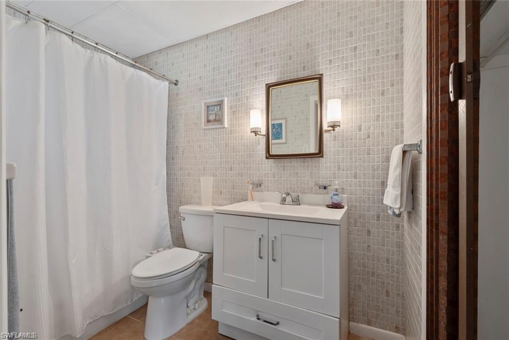 3550 Hazel Road Naples, FL 34104 - Photo 24 of 43 a bathroom with a toilet a sink and a mirror