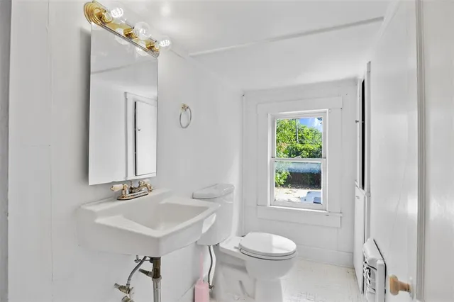 a bathroom with a sink a mirror a toilet and a window