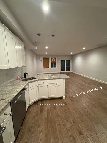 a large kitchen with stainless steel appliances granite countertop a large counter top and a stove with wooden floor