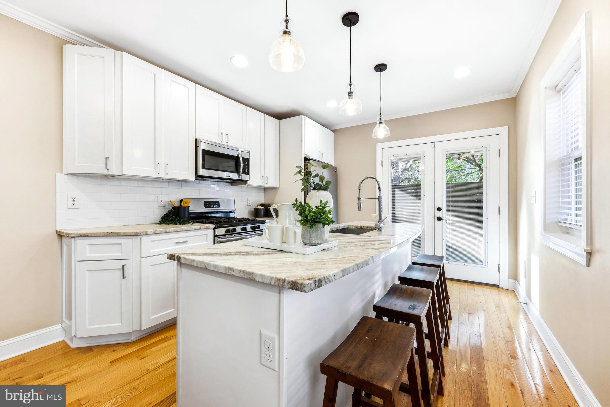 404 South Castle Street Baltimore, MD 21231 - Photo 11 of 47 a kitchen with a stove a sink a microwave a dining table and chairs