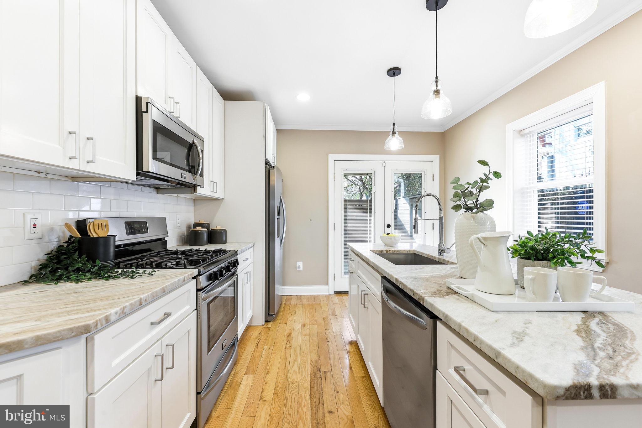 404 South Castle Street Baltimore, MD 21231 - Photo 16 of 47 a kitchen with stainless steel appliances granite countertop a sink a stove and a wooden floors