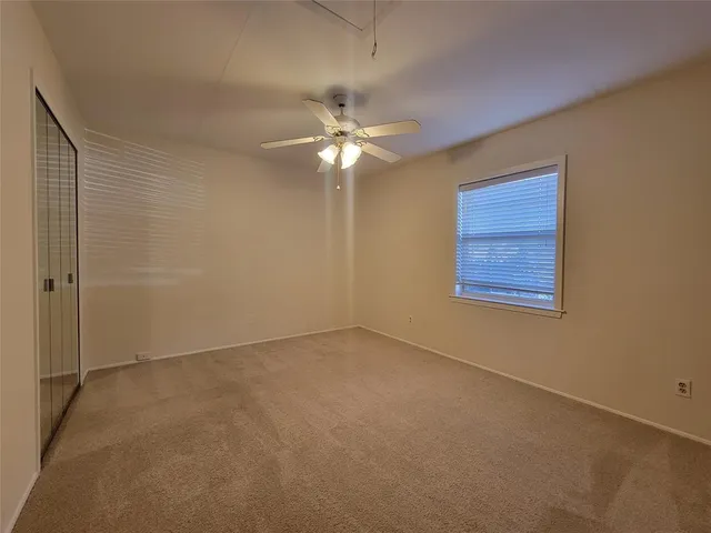 an empty room with a fan & a window