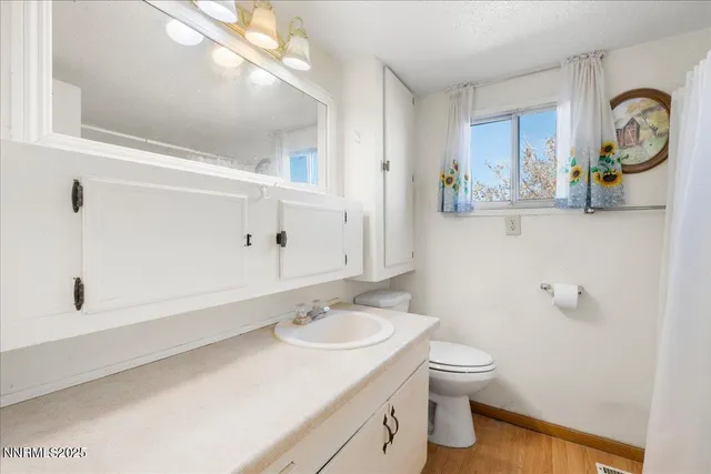 a bathroom with a granite countertop sink a toilet and shower