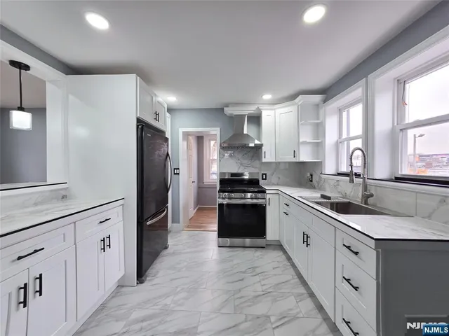 a large kitchen with stainless steel appliances granite countertop a sink and dishwasher a refrigerator with wooden cabinets