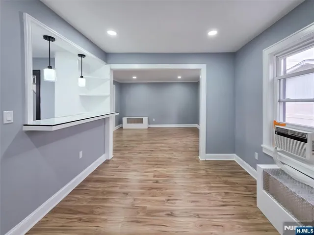 a view of a hallway with wooden floor and a living room