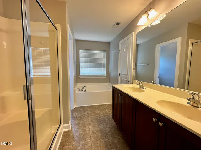 a bathroom with a double vanity sink a mirror and a bathtub