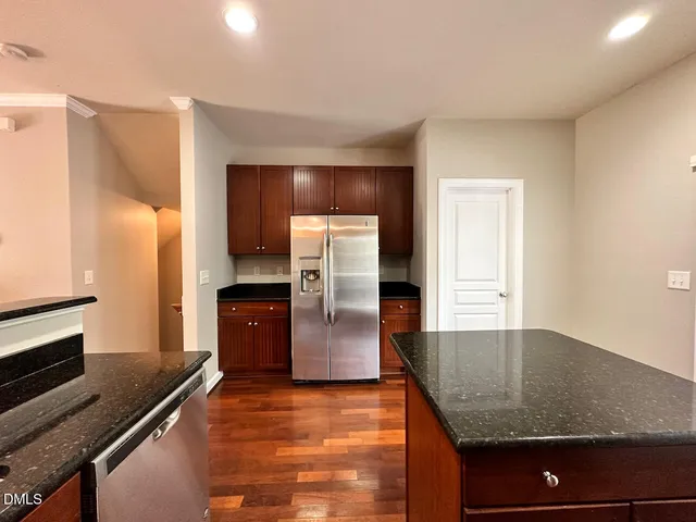 a kitchen with granite countertop a refrigerator and a stove top oven