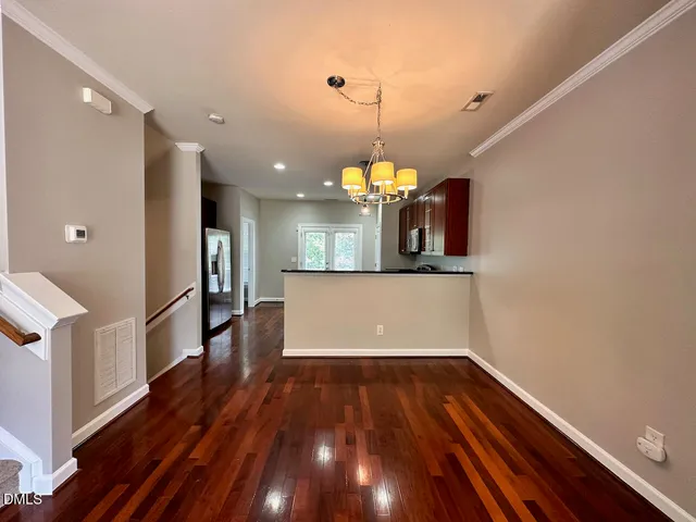 a view of a room with wooden floor kitchen appliances and a ceiling fan