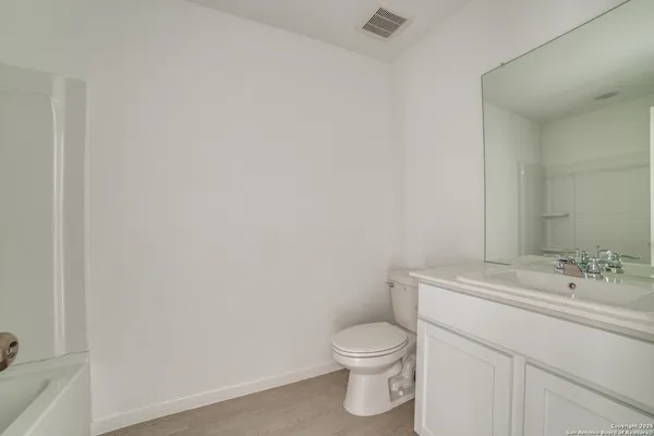 a bathroom with a toilet sink vanity and mirror