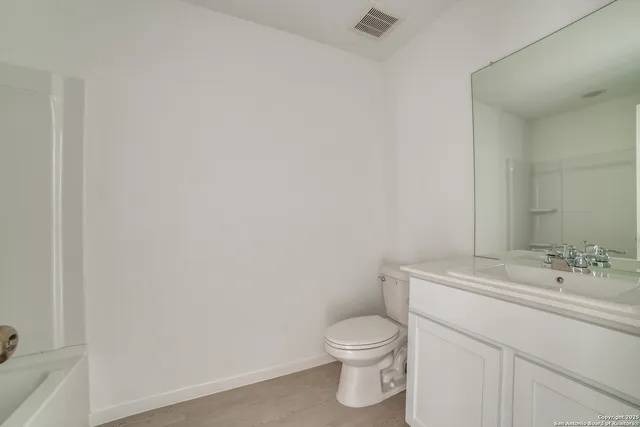 a bathroom with a toilet sink vanity and mirror