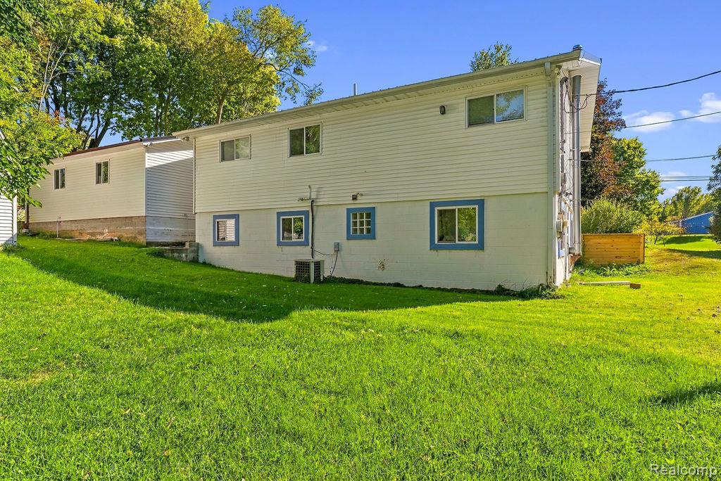 87 Burley Road Columbiaville, MI 48421 - Photo 28 of 31 Expansive grassy yard area with a two-story residence featuring white siding and blue-trimmed windows