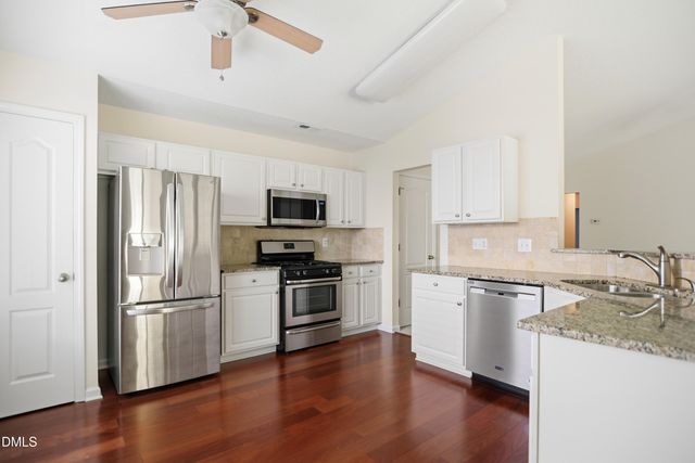 a kitchen with granite countertop stainless steel appliances a refrigerator cabinets and wooden floor
